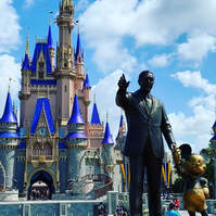 Front view of Disney World with the Walt Disney and Mickey Mouse statue in front
